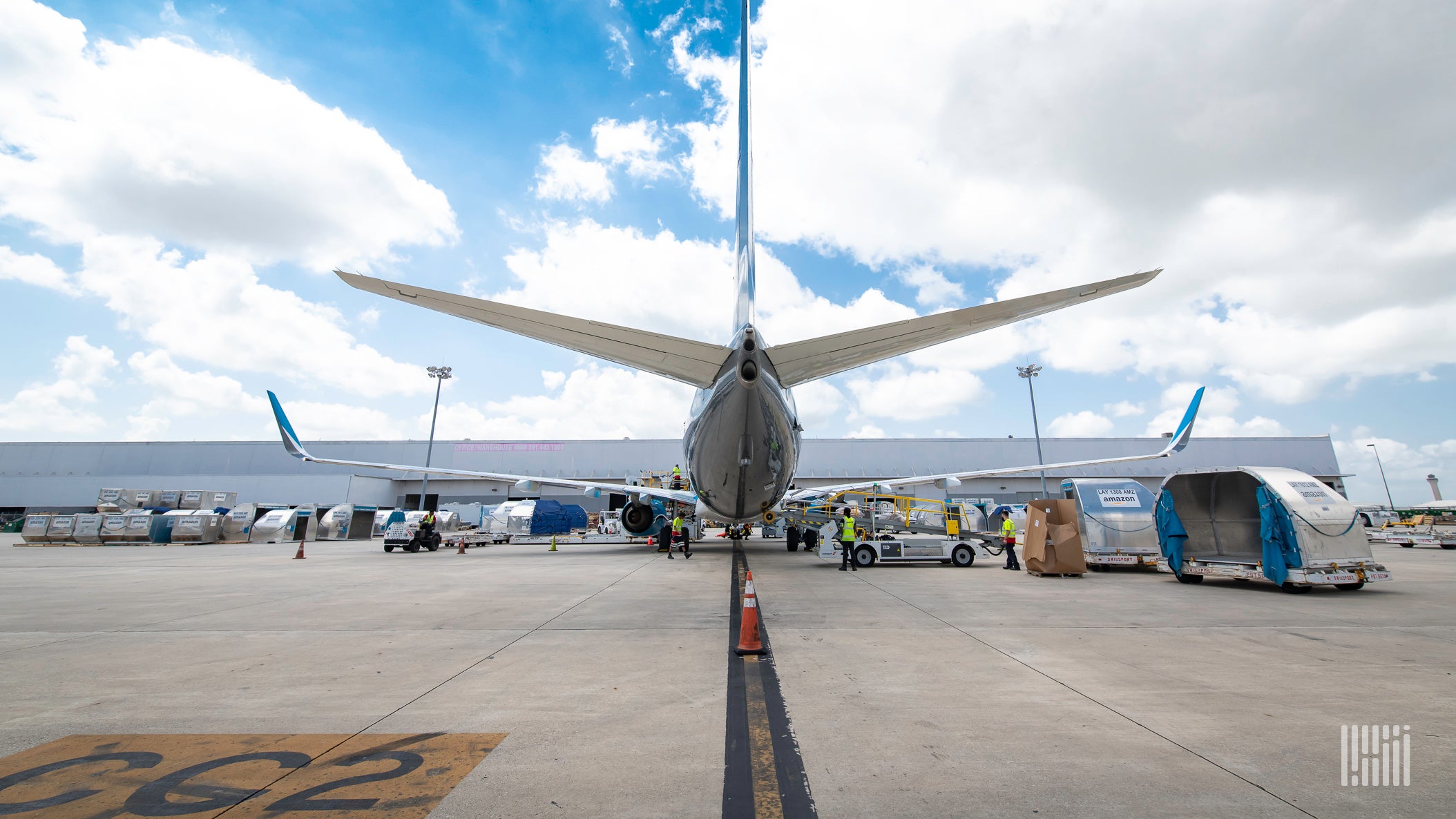 Rear view of a commercial jet parked at the terminal with a cargo container sitting on the tarmac.