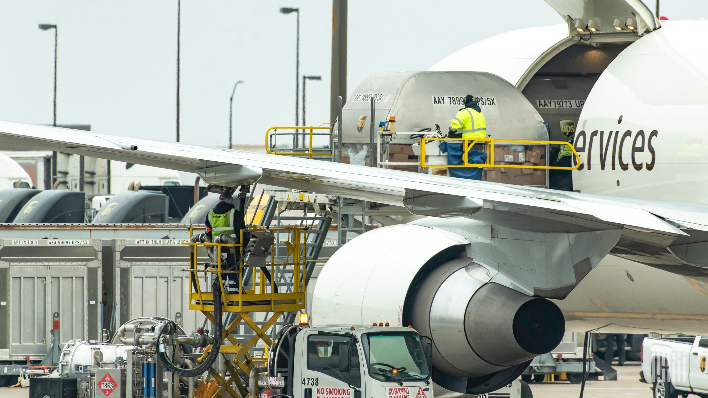 A jet being loaded with cargo and getting refueled at an airport.