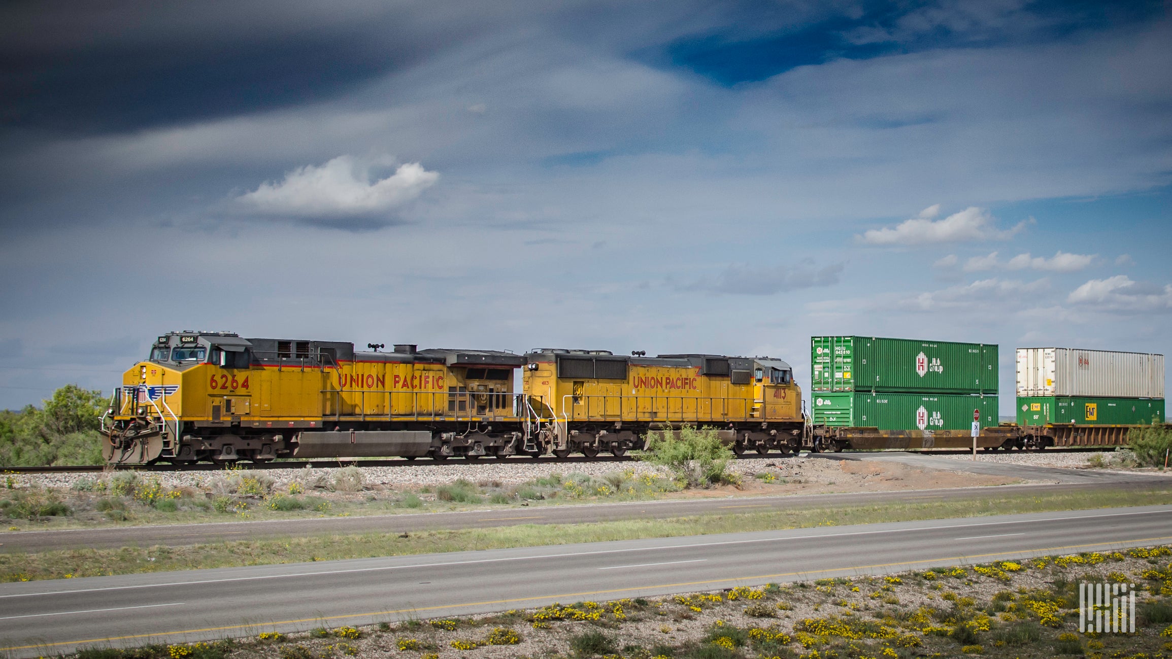 A Union Pacific train hauls intermodal containers through a field.