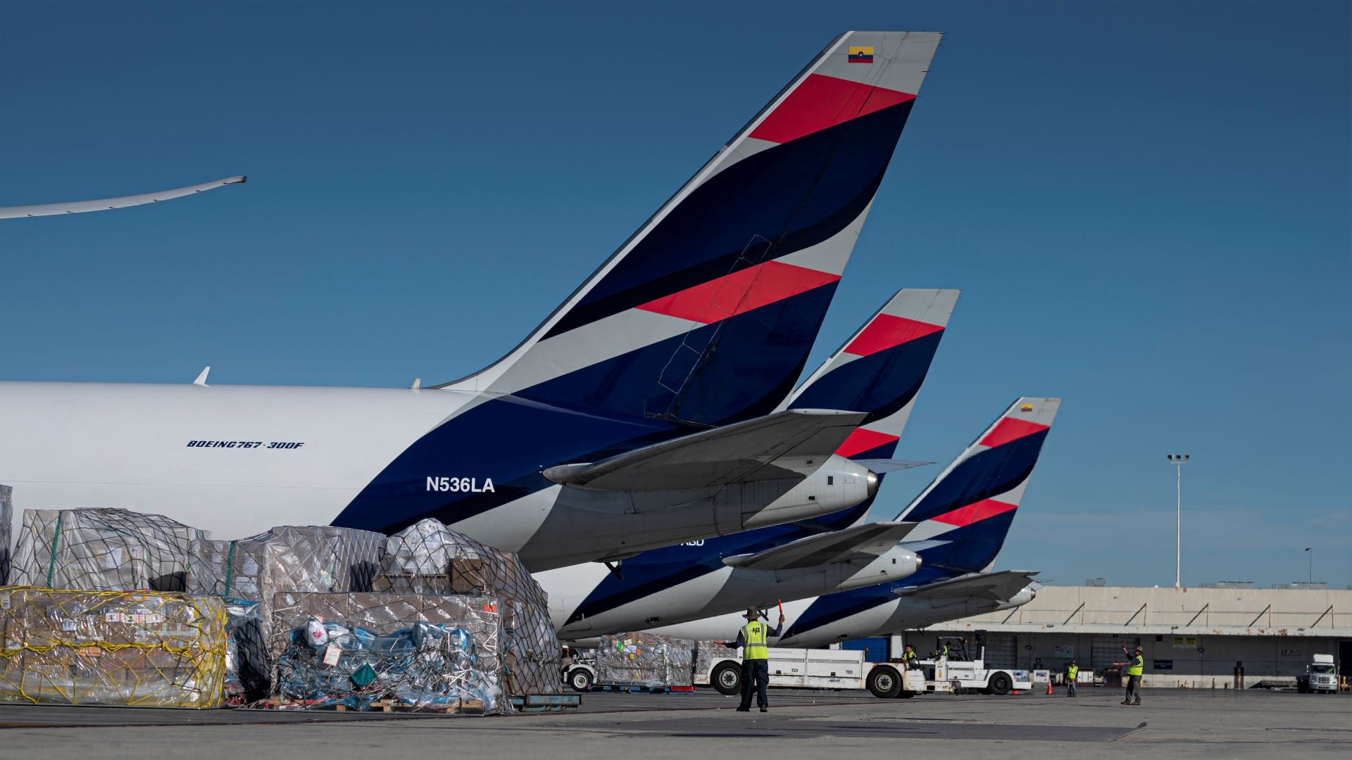 A row of aircraft, with tail view only. Blue and red color scheme.