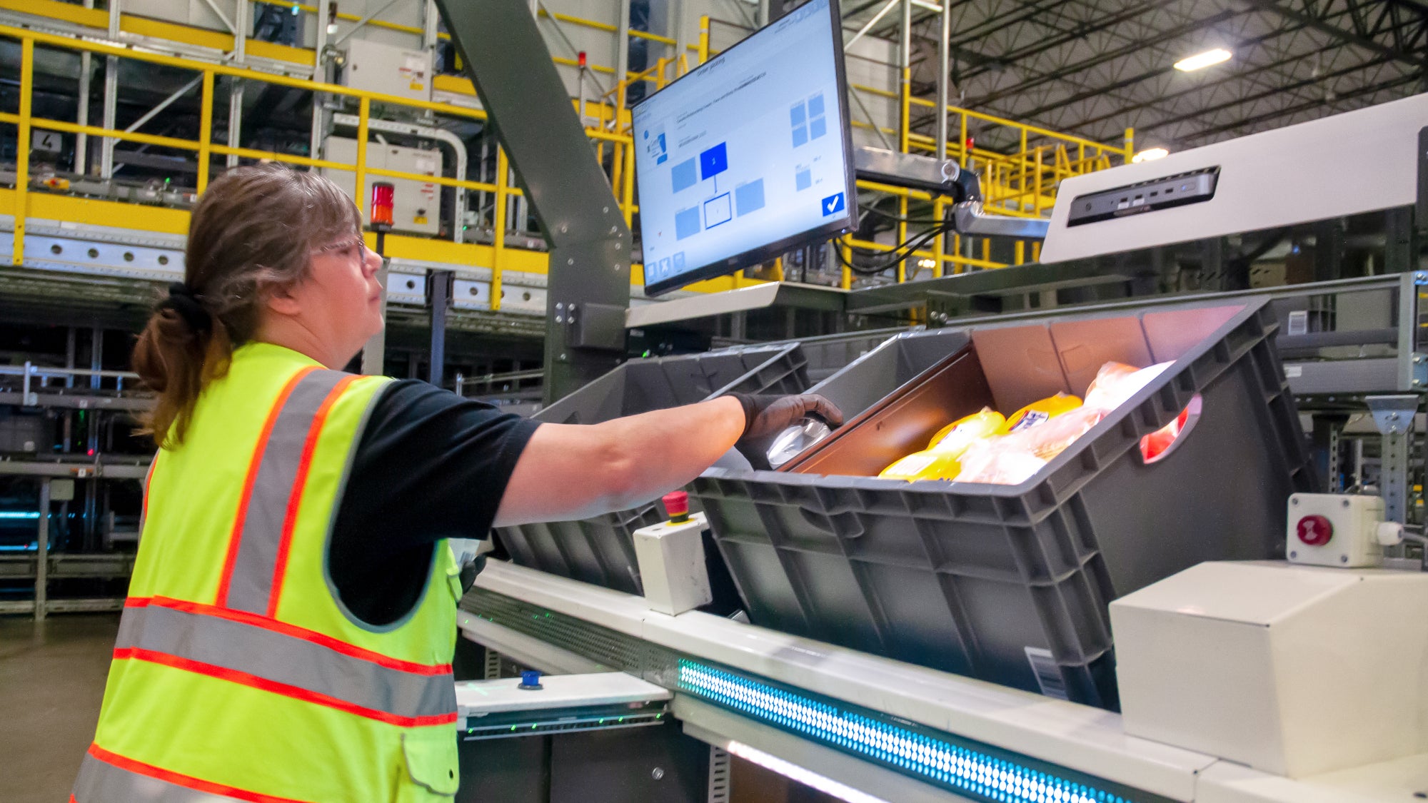 Walmart associate fills totes on e-commerce fulfillment line