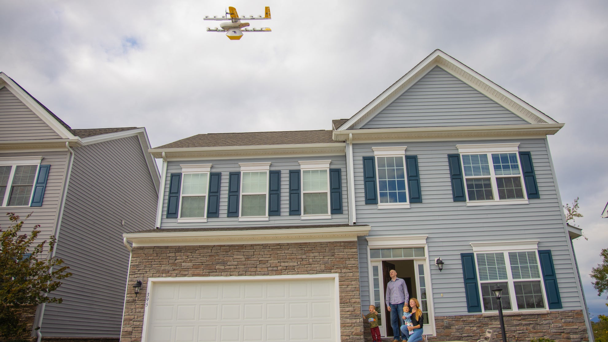 drone hovers over home as residents wait for delivery in their front yard