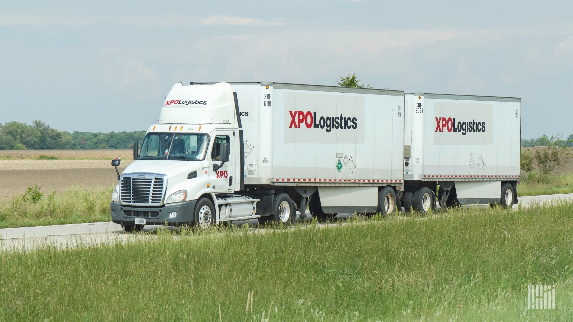 White XPO truck on the highway hauling two trailers