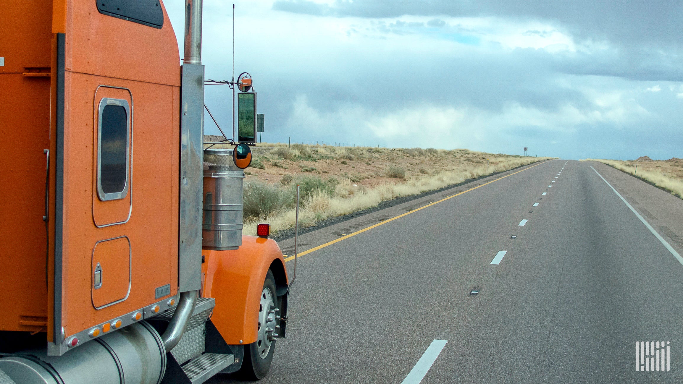 An orange truck on a highway.