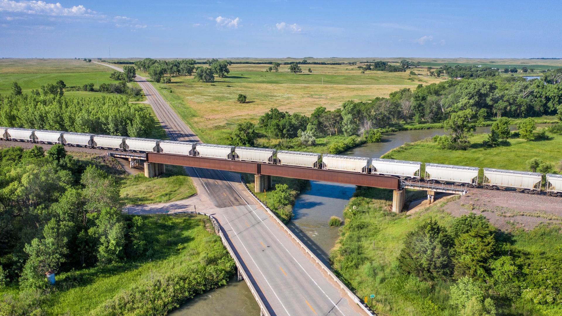 A train with hopper cars crosses a bridge.