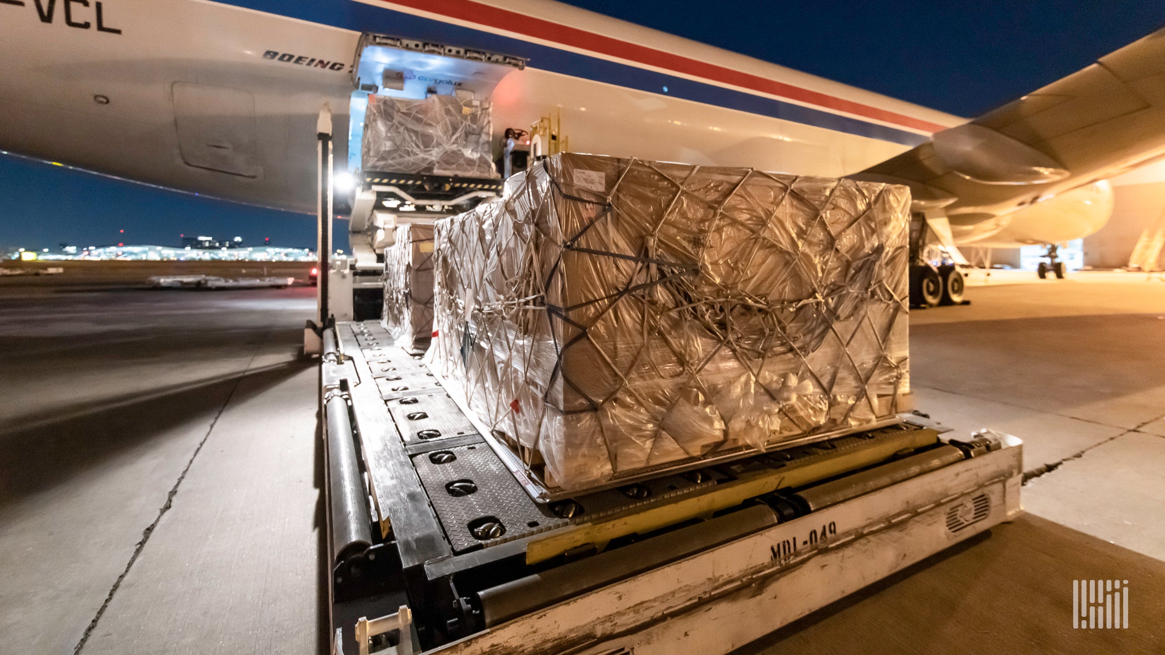 Cargo pallet being loaded on a large aircraft at night.