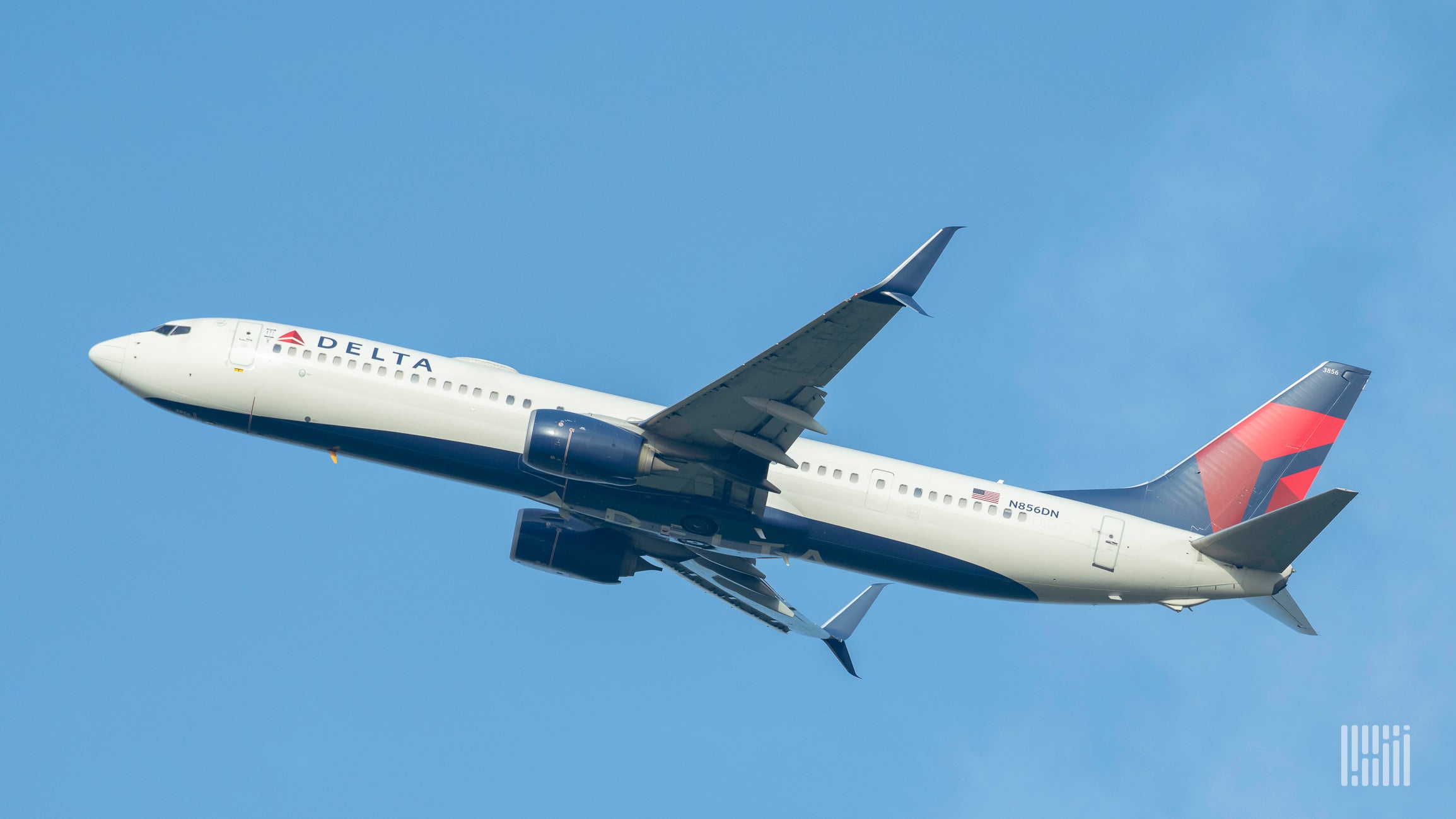 A blue, red and white Delta Air Lines plane in the sky, view from below.