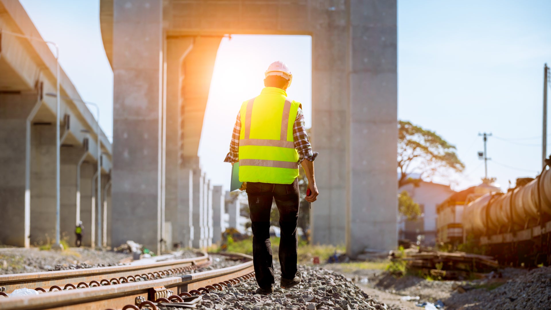 A railroad worker walks next to some railroad track.