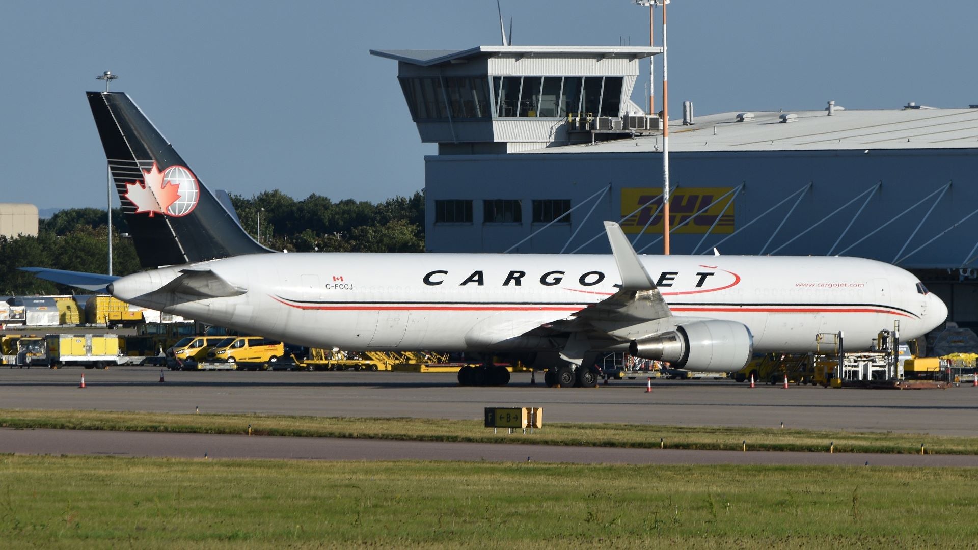 A large, white Cargojet freighter with blue tail parked by airport control tower.