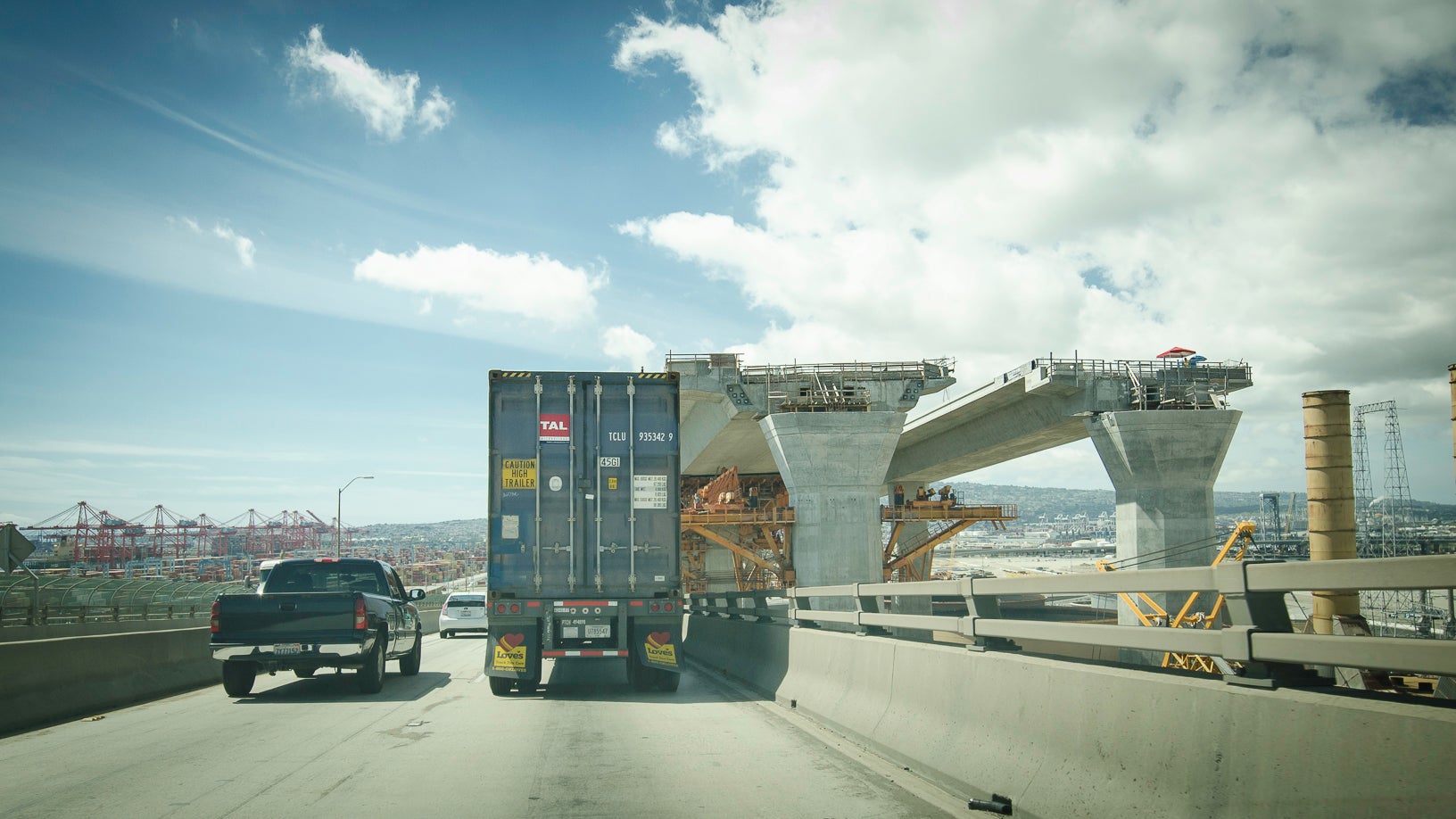 Truck passing by bridge under construction.