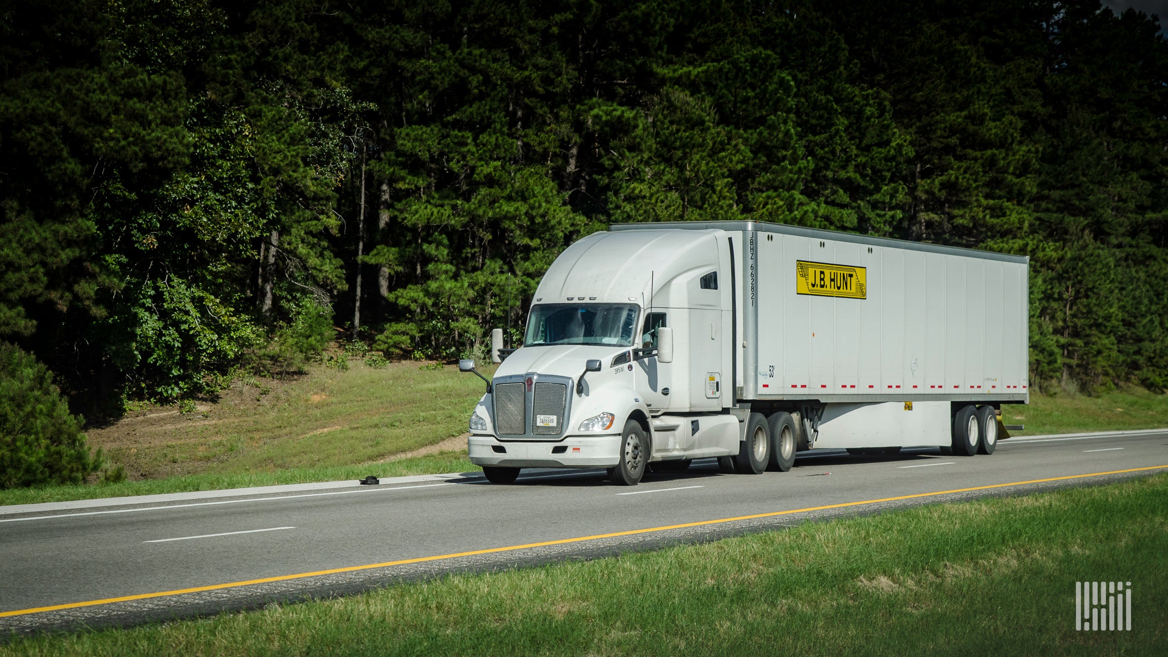 A white J.B. Hunt tractor pulling a white trailer on highway