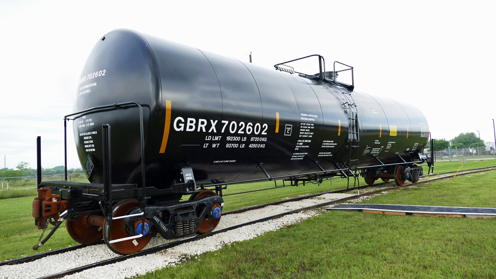 A tank car sits in a grassy field.