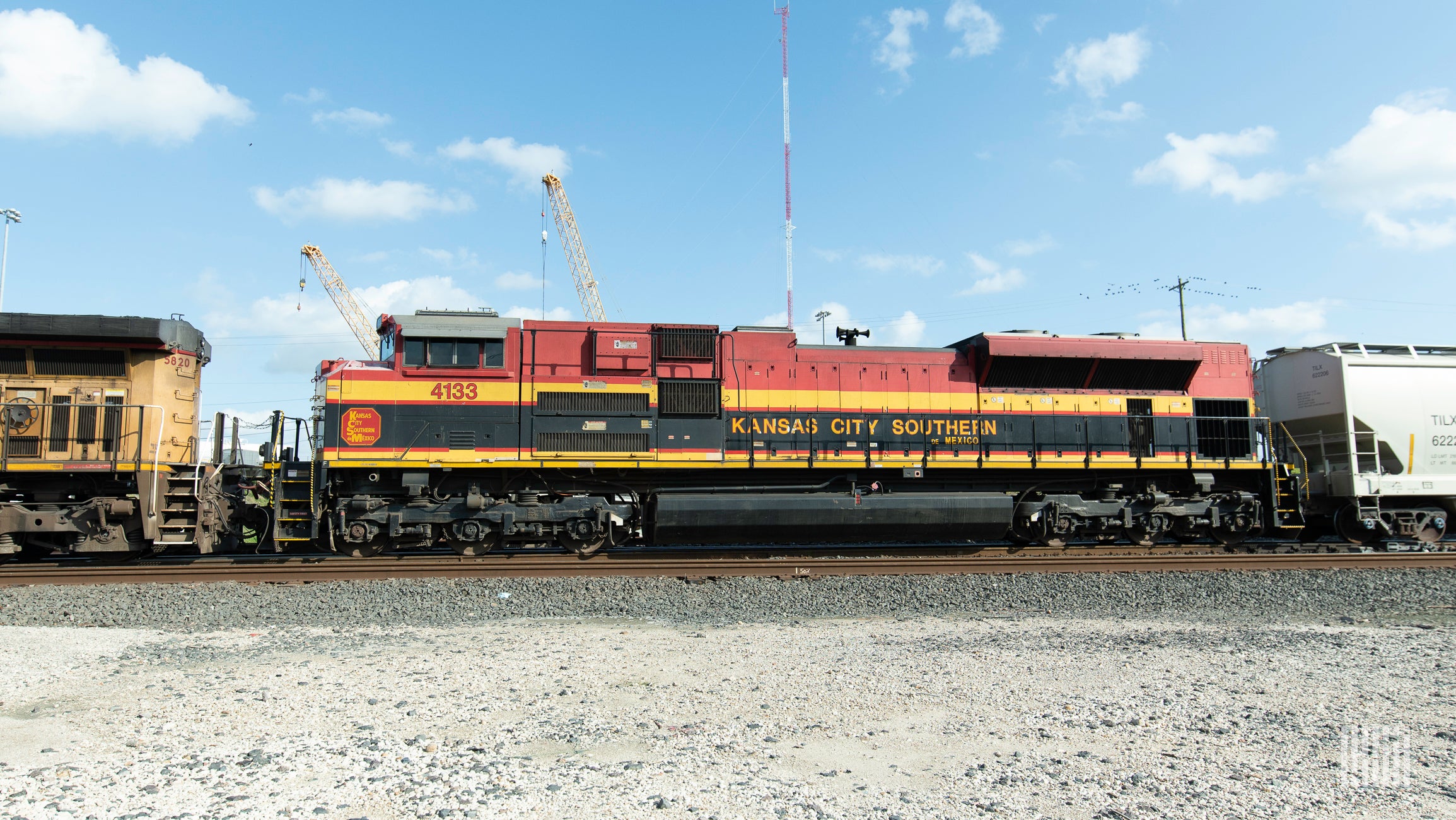 A train that says Kansas City Southern on its side is parked at a rail yard.