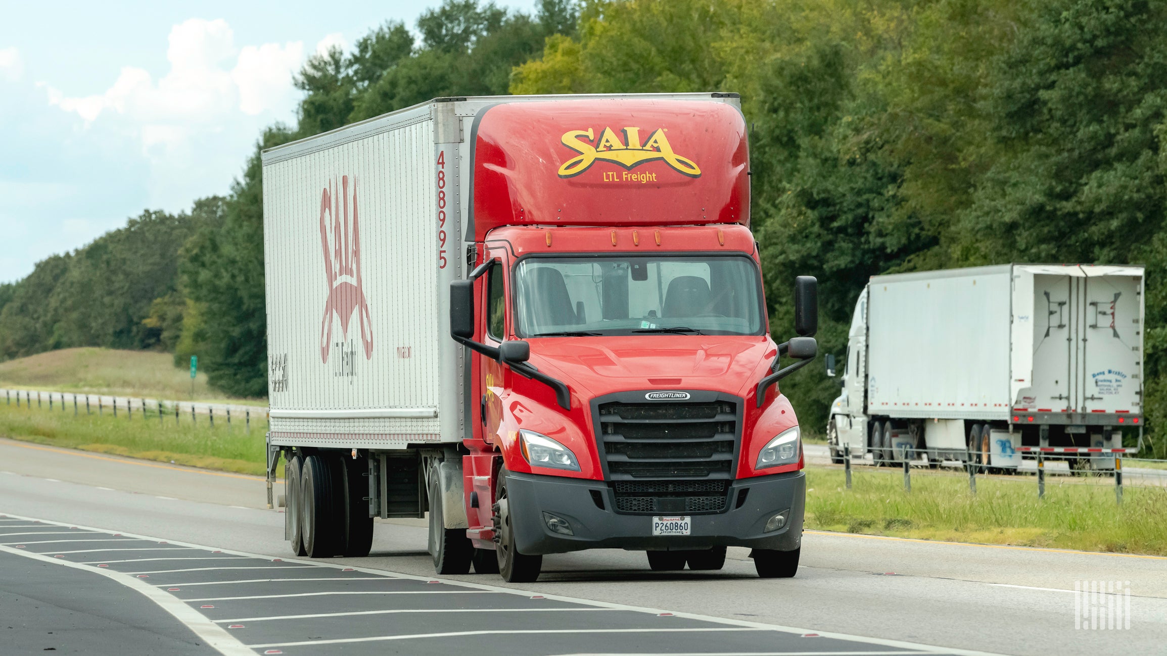 A red Saia tractor and white trailer on the highway