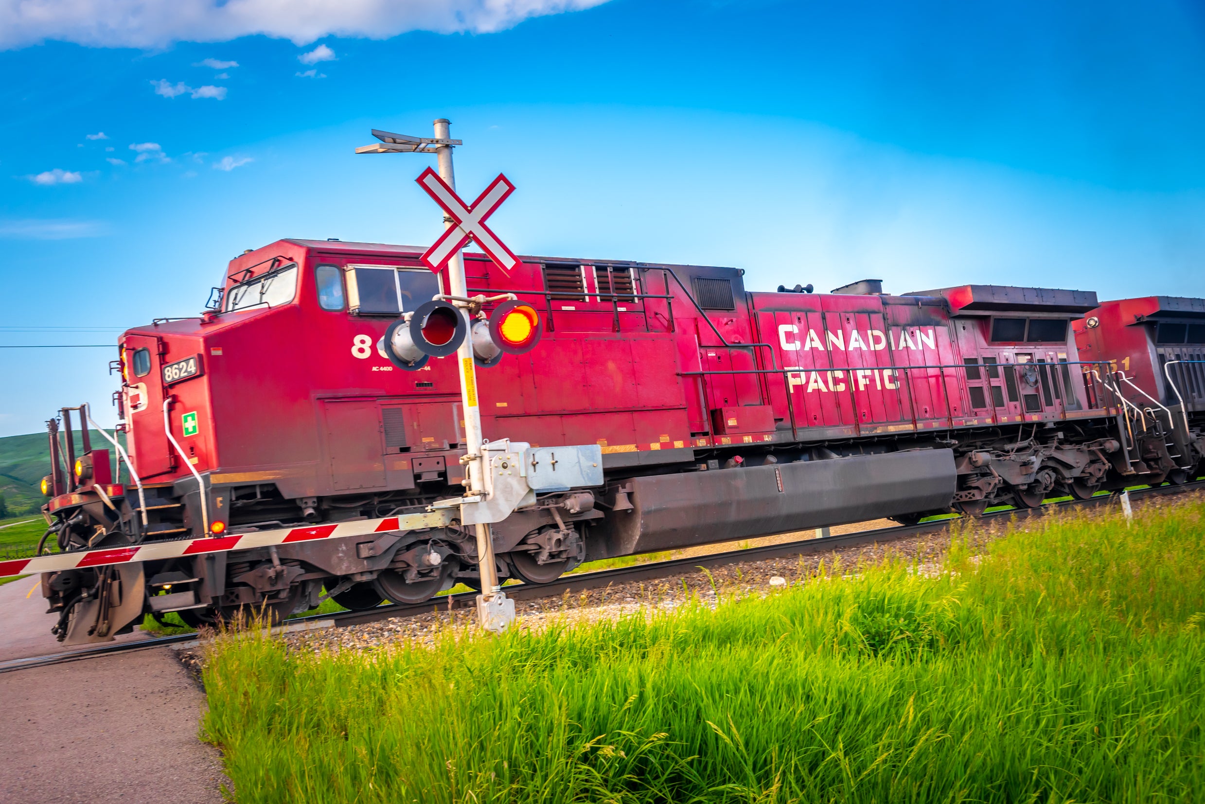 A red train with the words "Canadian Pacific" on its side travels through a railroad crossing.