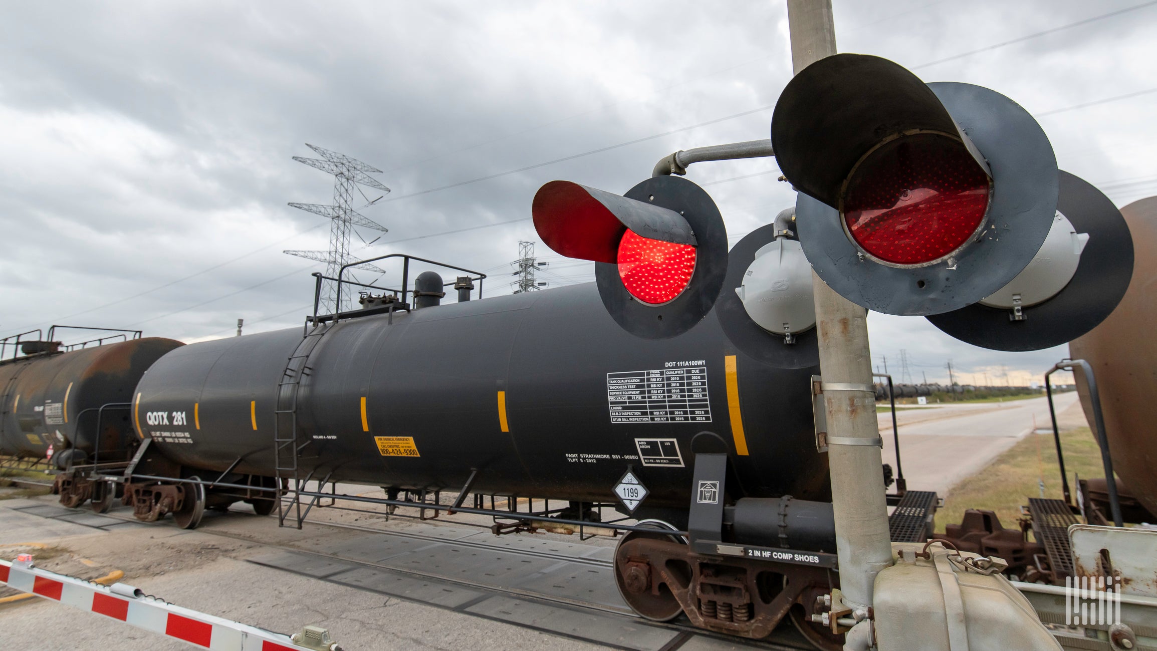 A train hauling tank cars passes through a railroad crossing.