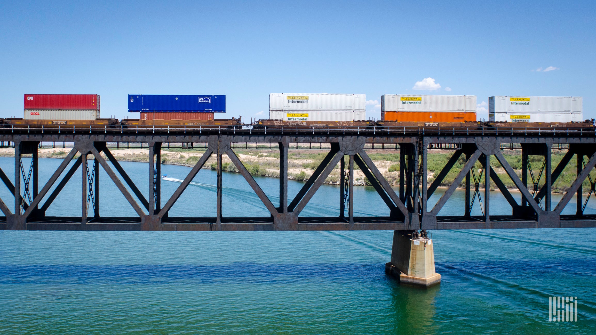 A train hauling intermodal containers travels on a bridge.