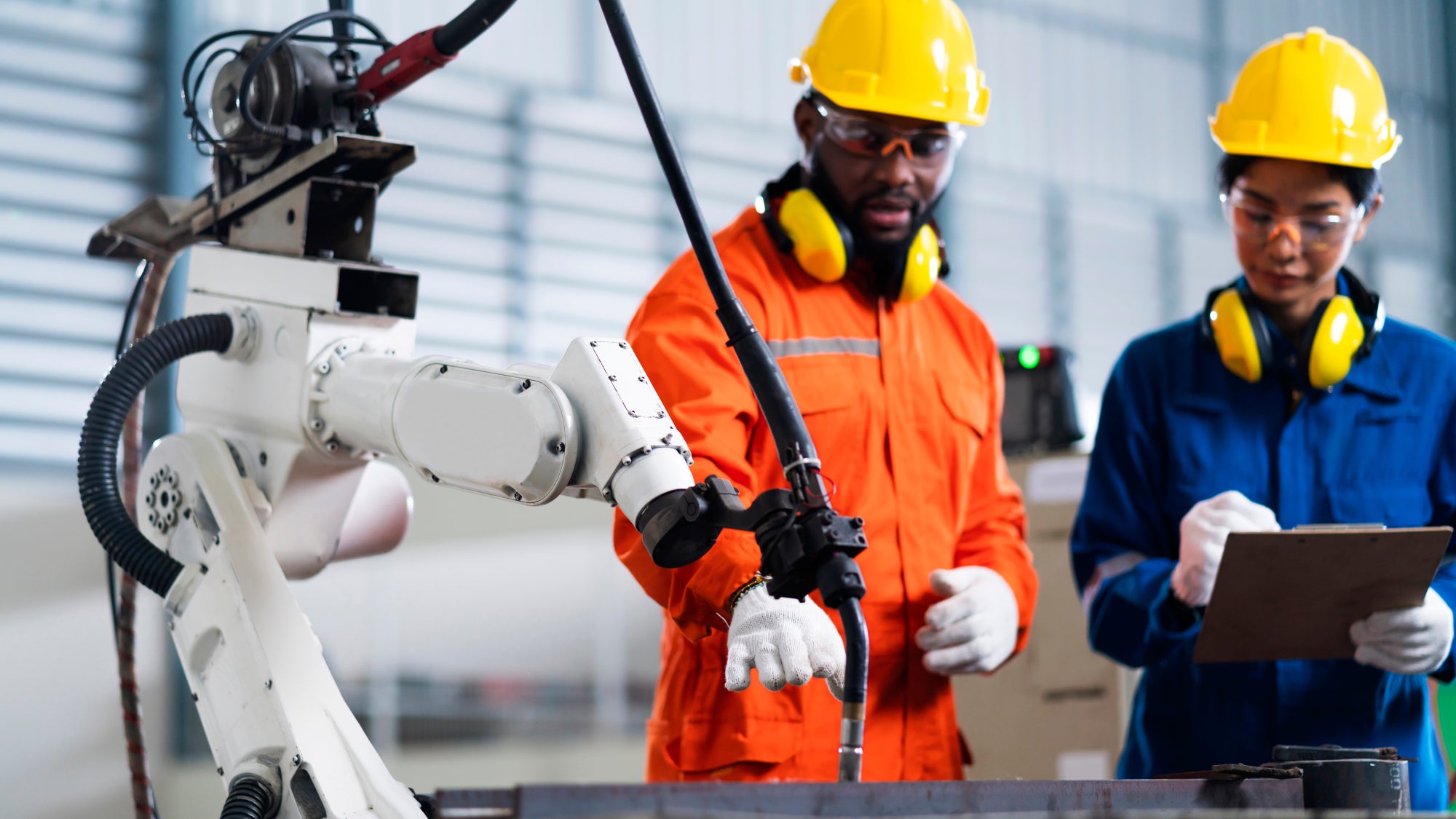 2 men standing next to manufacturing robot