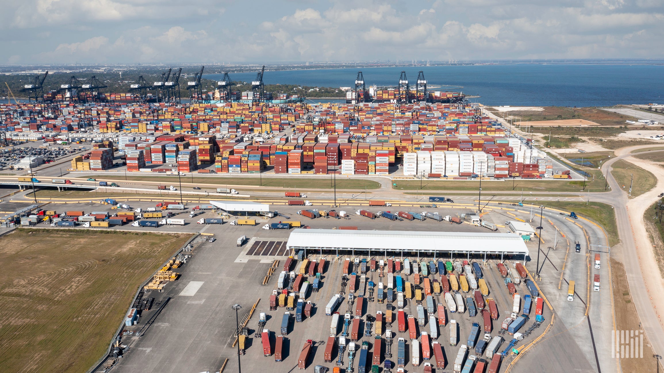 Semi trucks wait in lines to enter a maritime port.