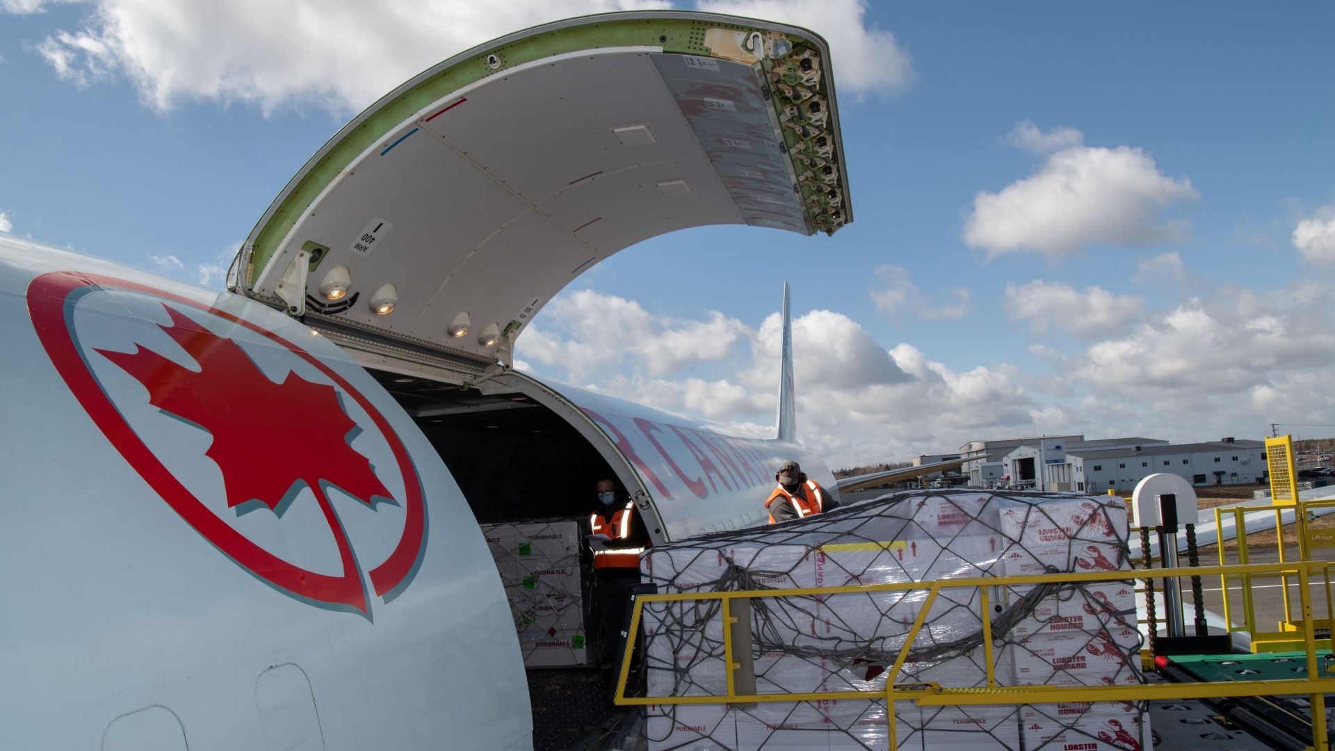 Close-up side view of an Air Canada jet with red maple leaf and cargo door open.