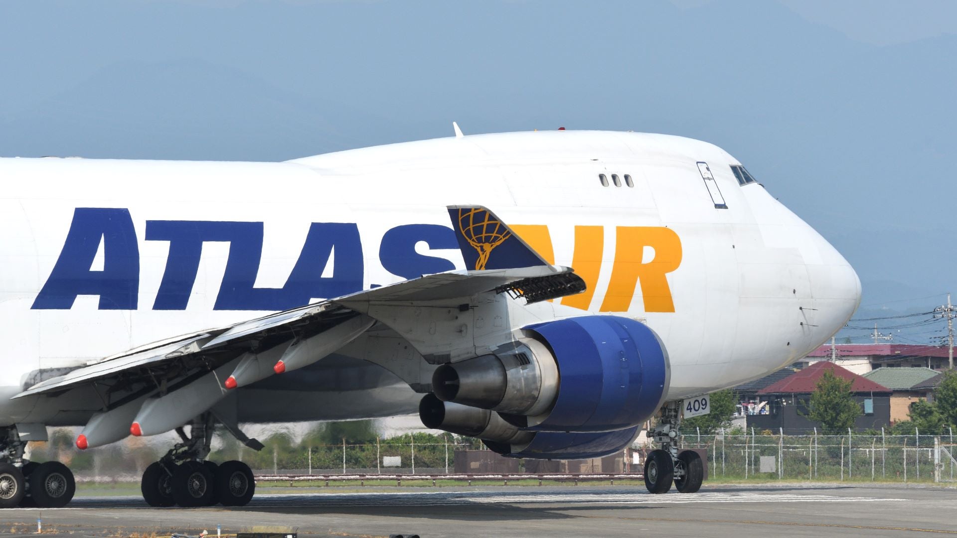 Close up of Atlas Air 747 jumbo jet. Front-half of white aircraft with blue and gold lettering.