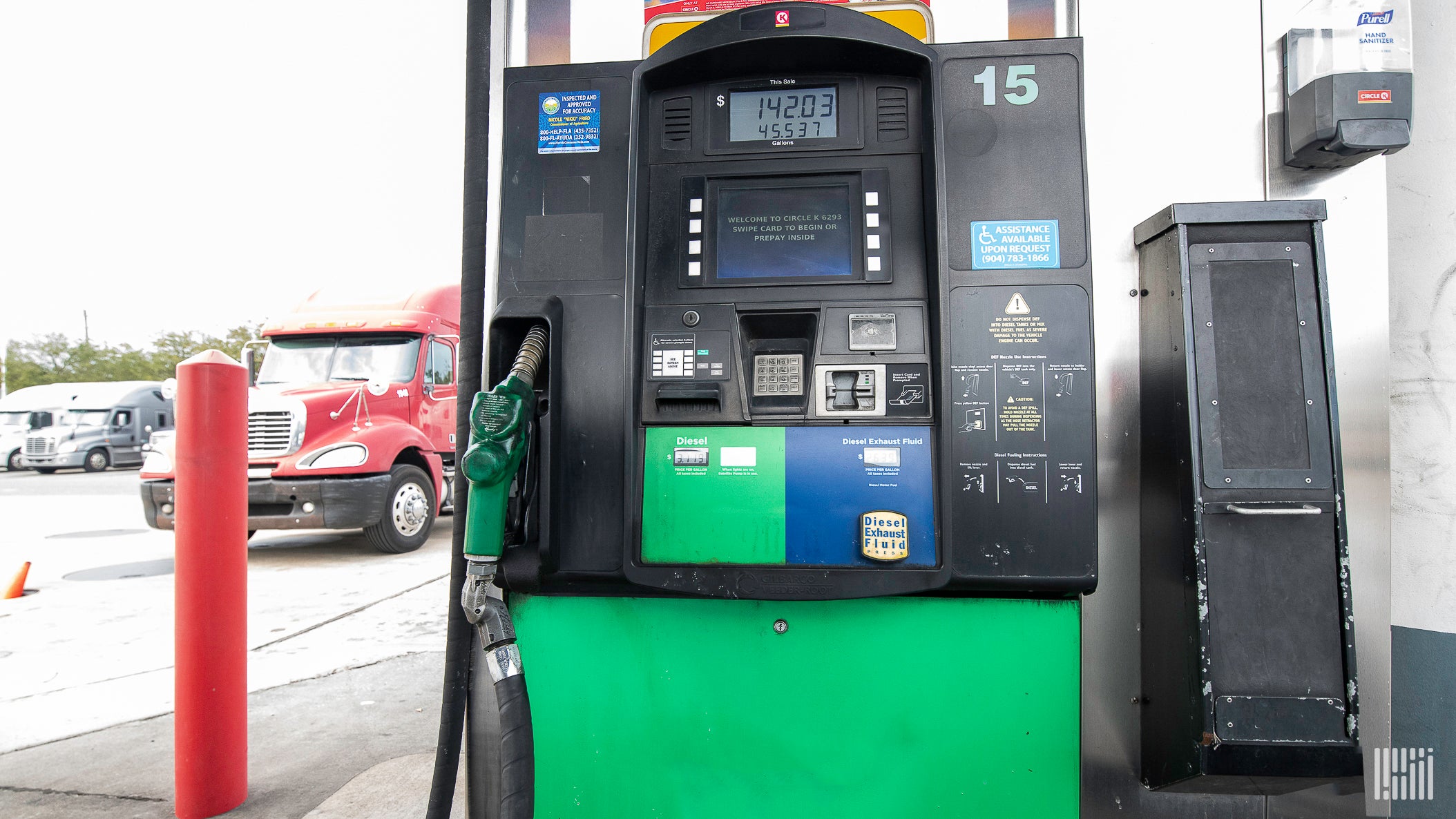 A red truck is behind a diesel fuel pump.