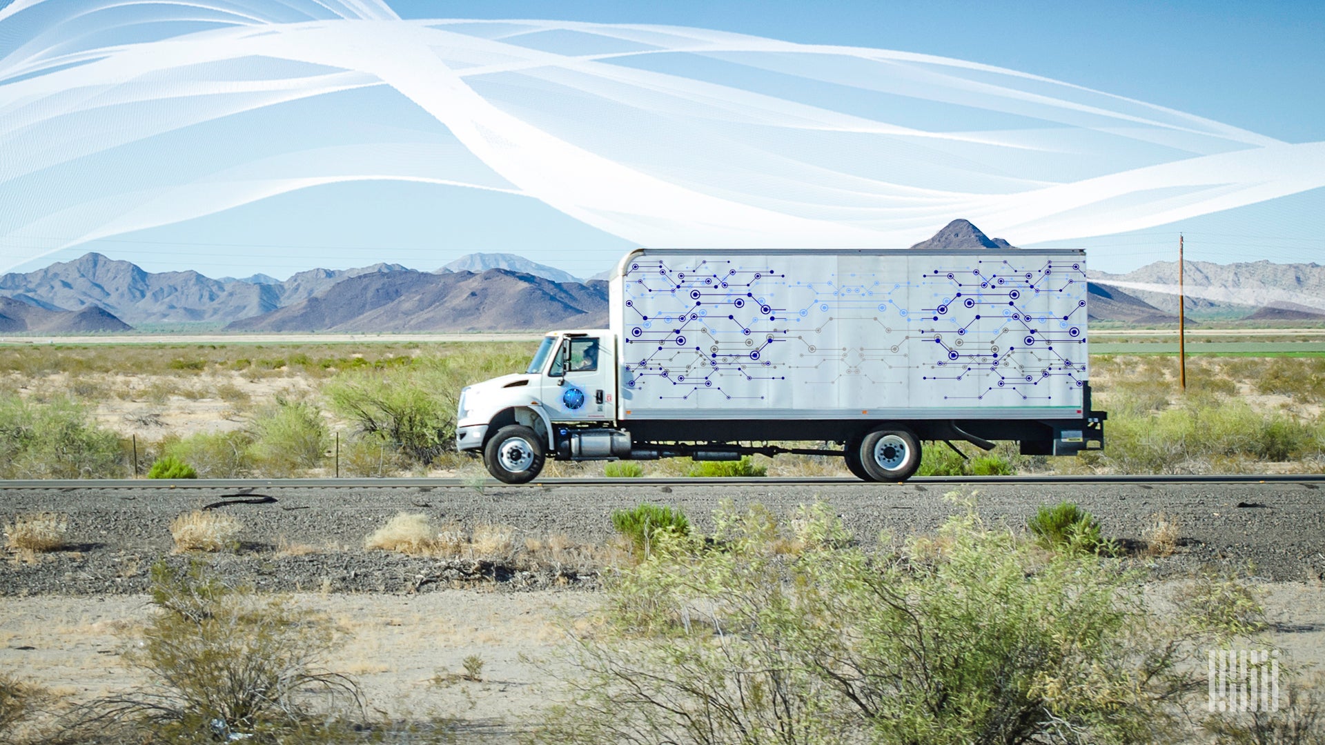 A white truck travels on a road with mountains and technology icons in the background.