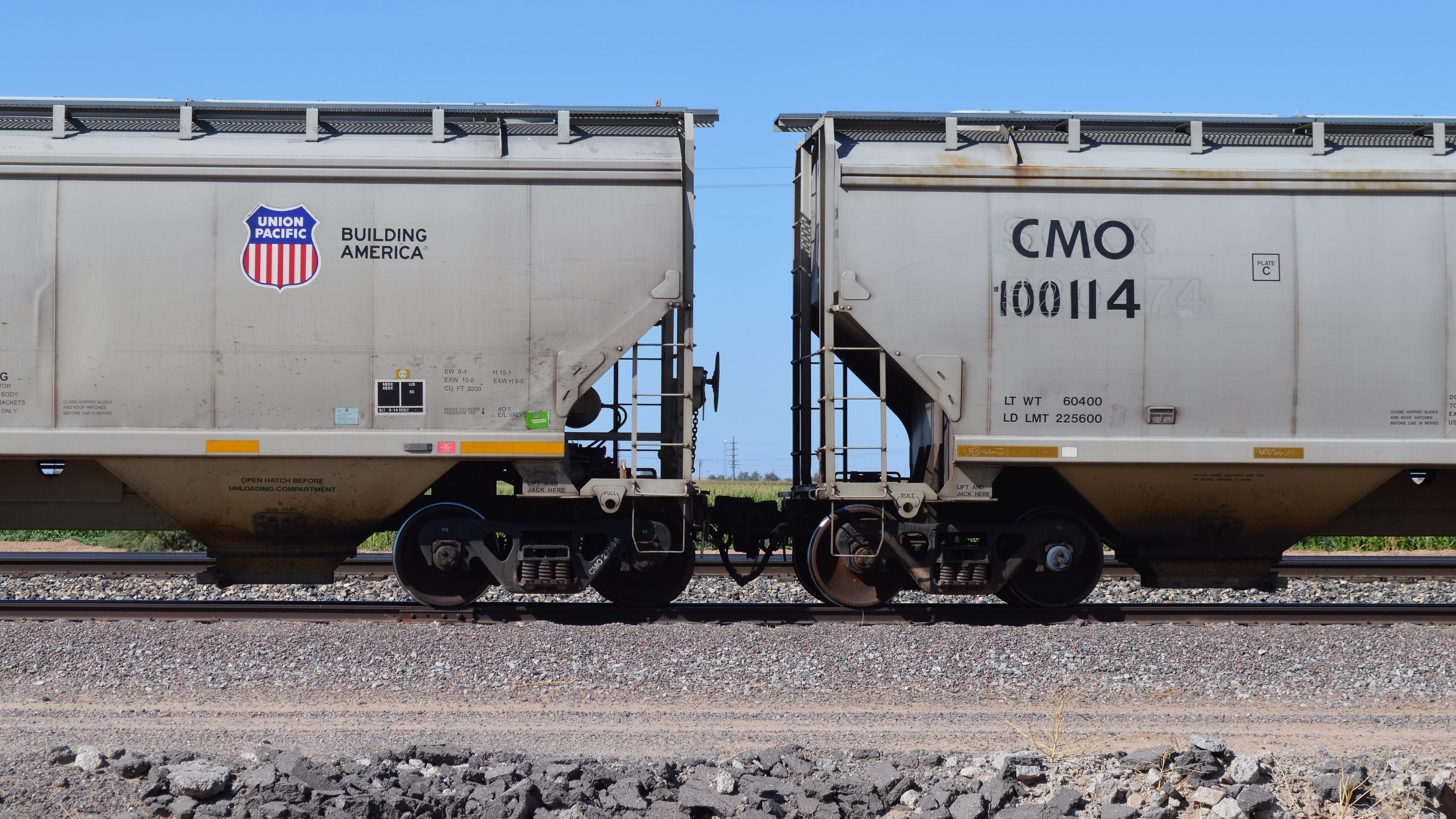 Two hopper rail cars sit on a rail track.