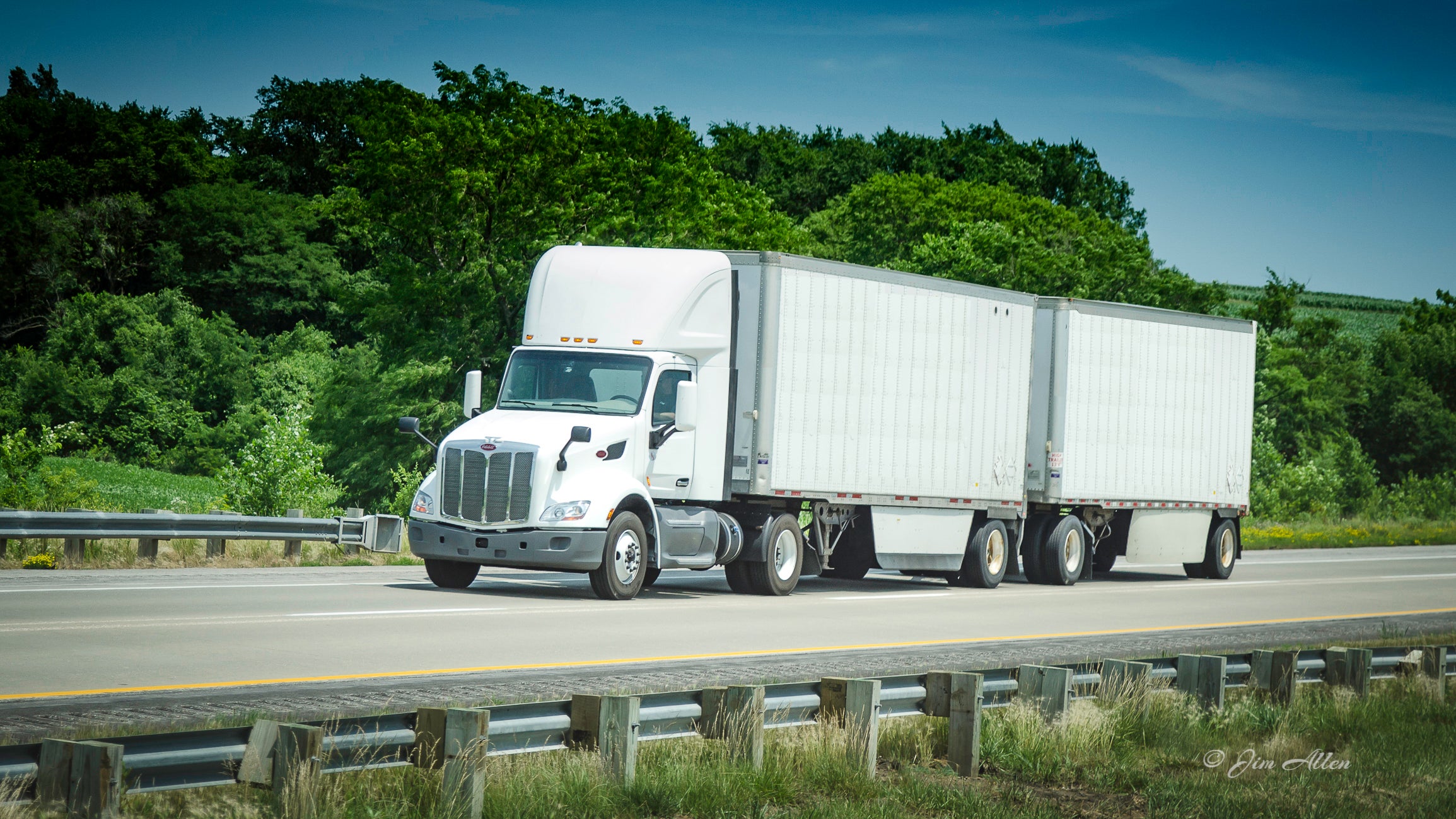 A white tractor pulling two white LTL trailers