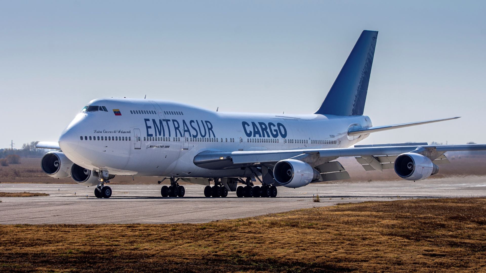 A white-and-blue jumbo jet on a runway.