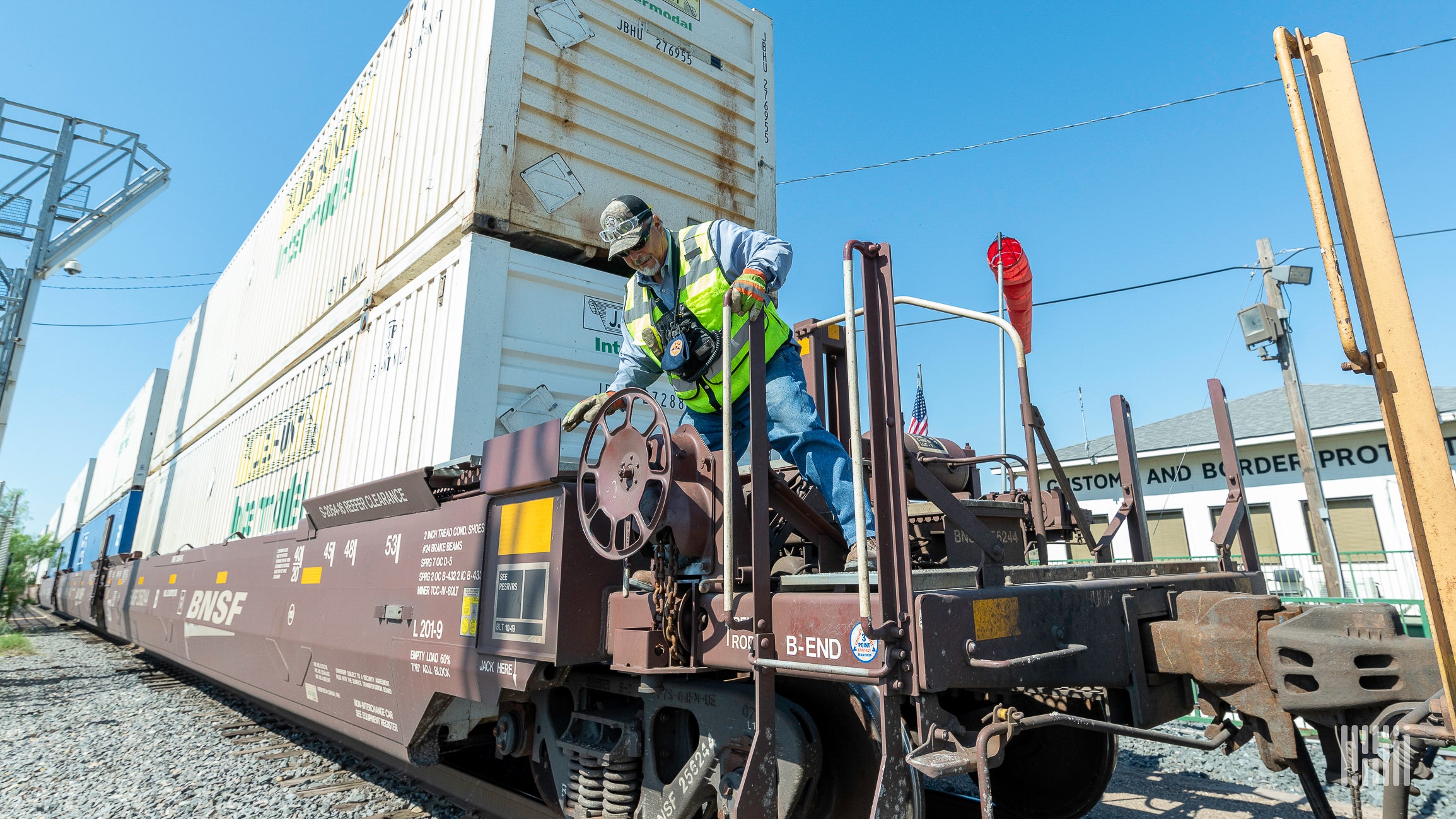 A man inspects a railcar carrying an intermodal container.