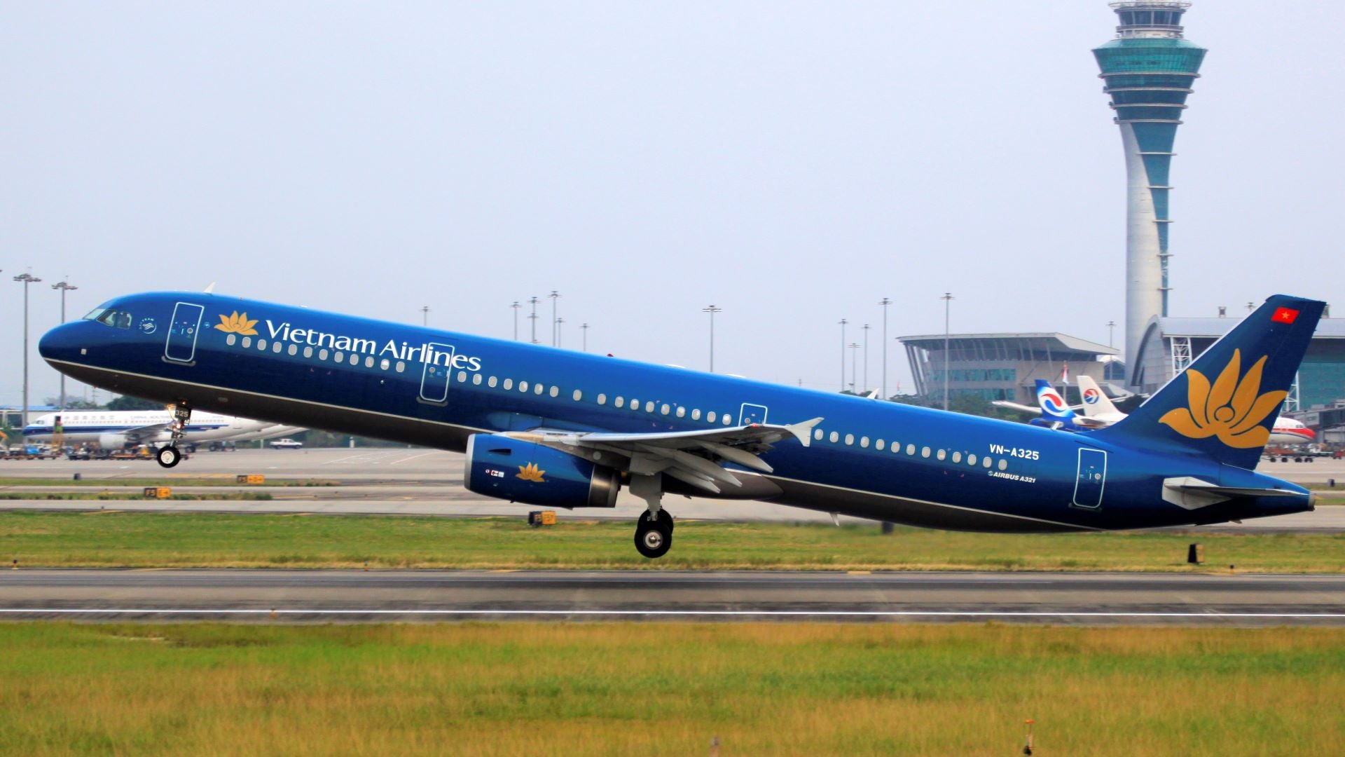 A teal-colored Vietnam Airlines jet lifts off from runway.