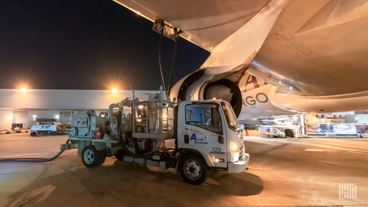 A fuel truck refills a plane at night.