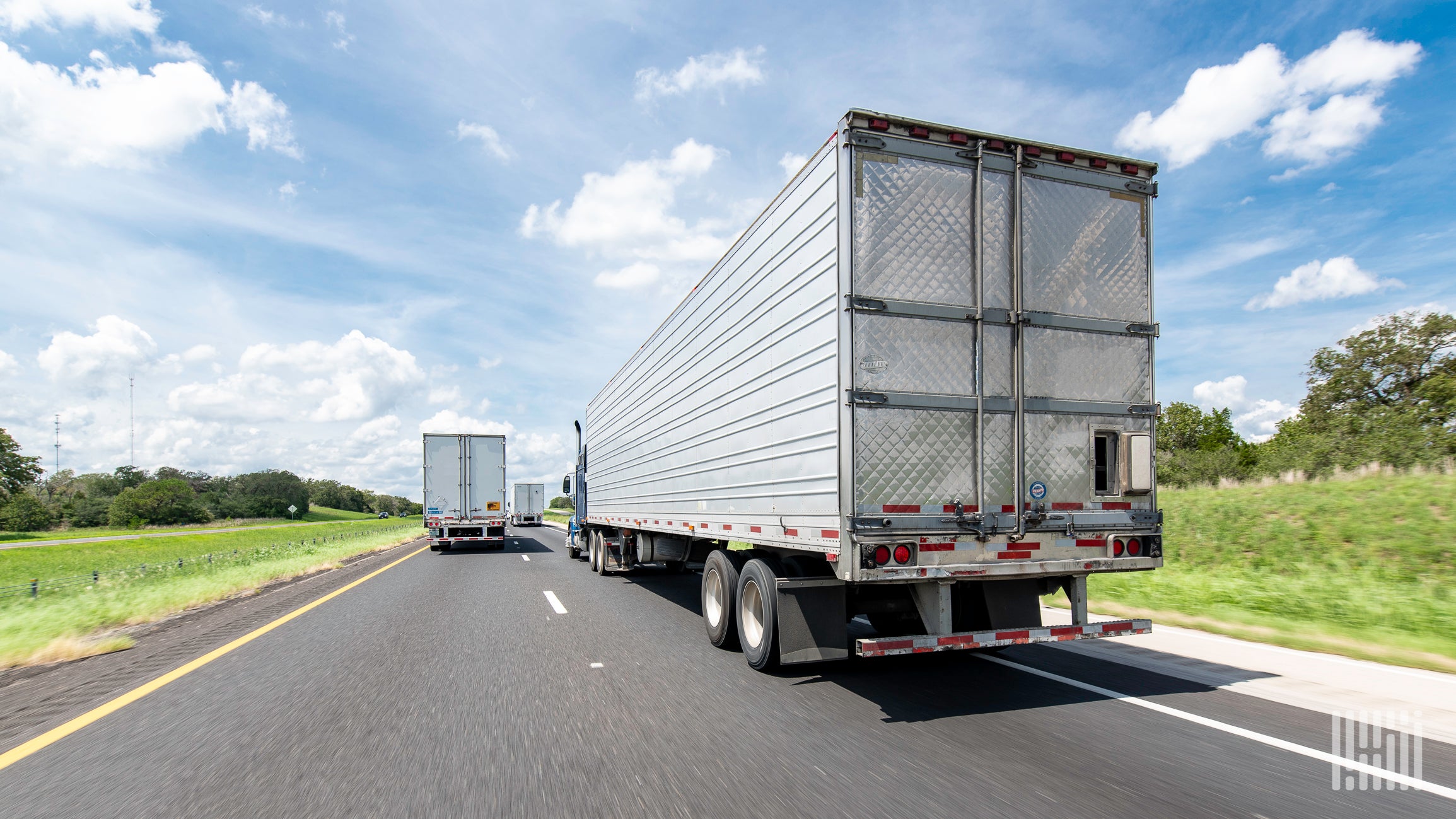 Semi trucks are traveling down a highway.