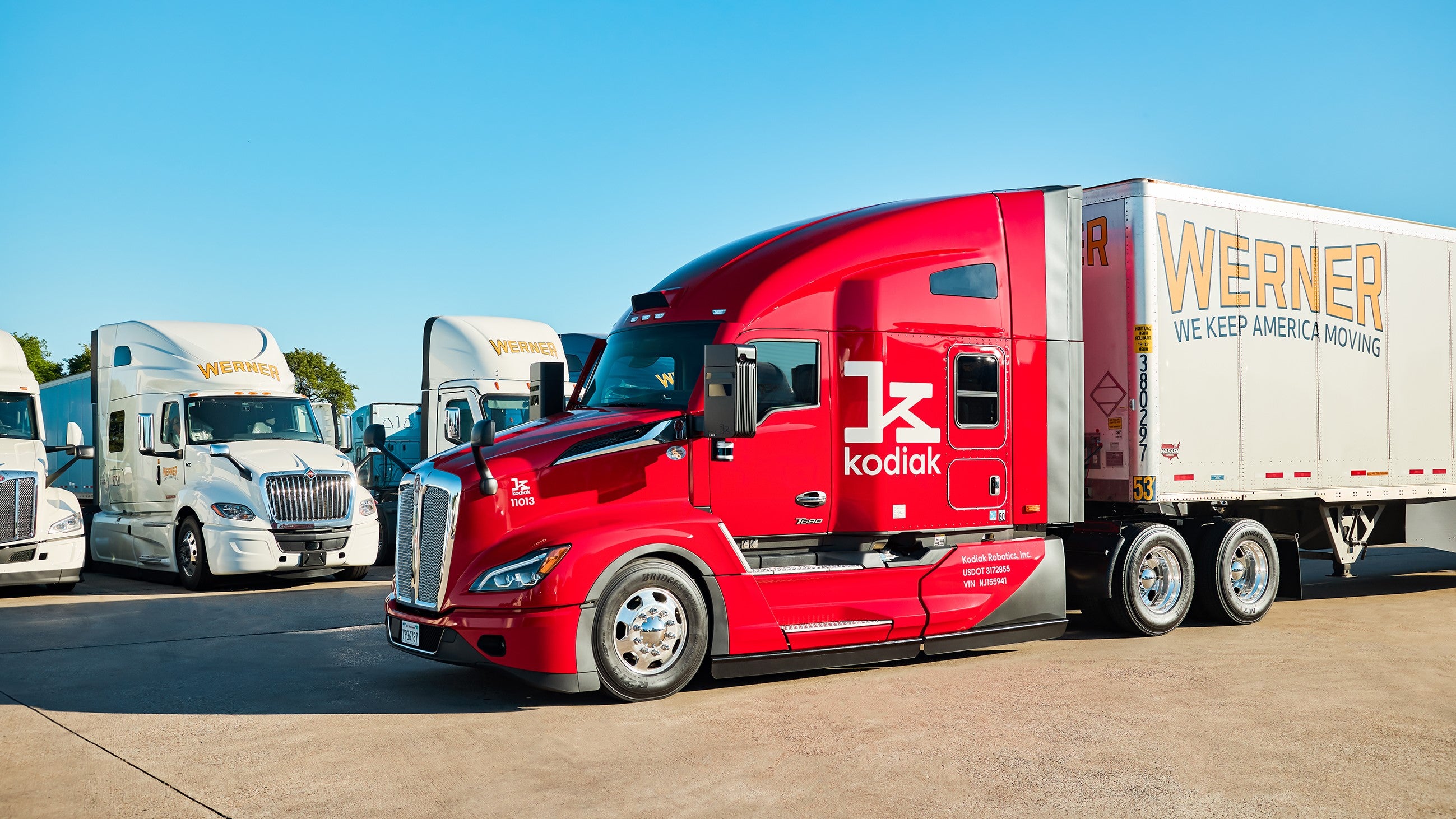 Red Kodiak robotics truck in front of row of Werner Enterprises trucks