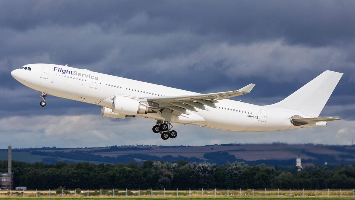 A large white passenger jet takes off with grey clouds in background.