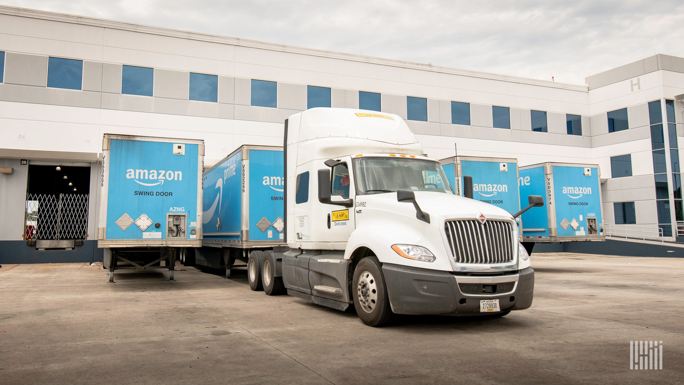 A tractor is picking up an Amazon trailer at a warehouse.