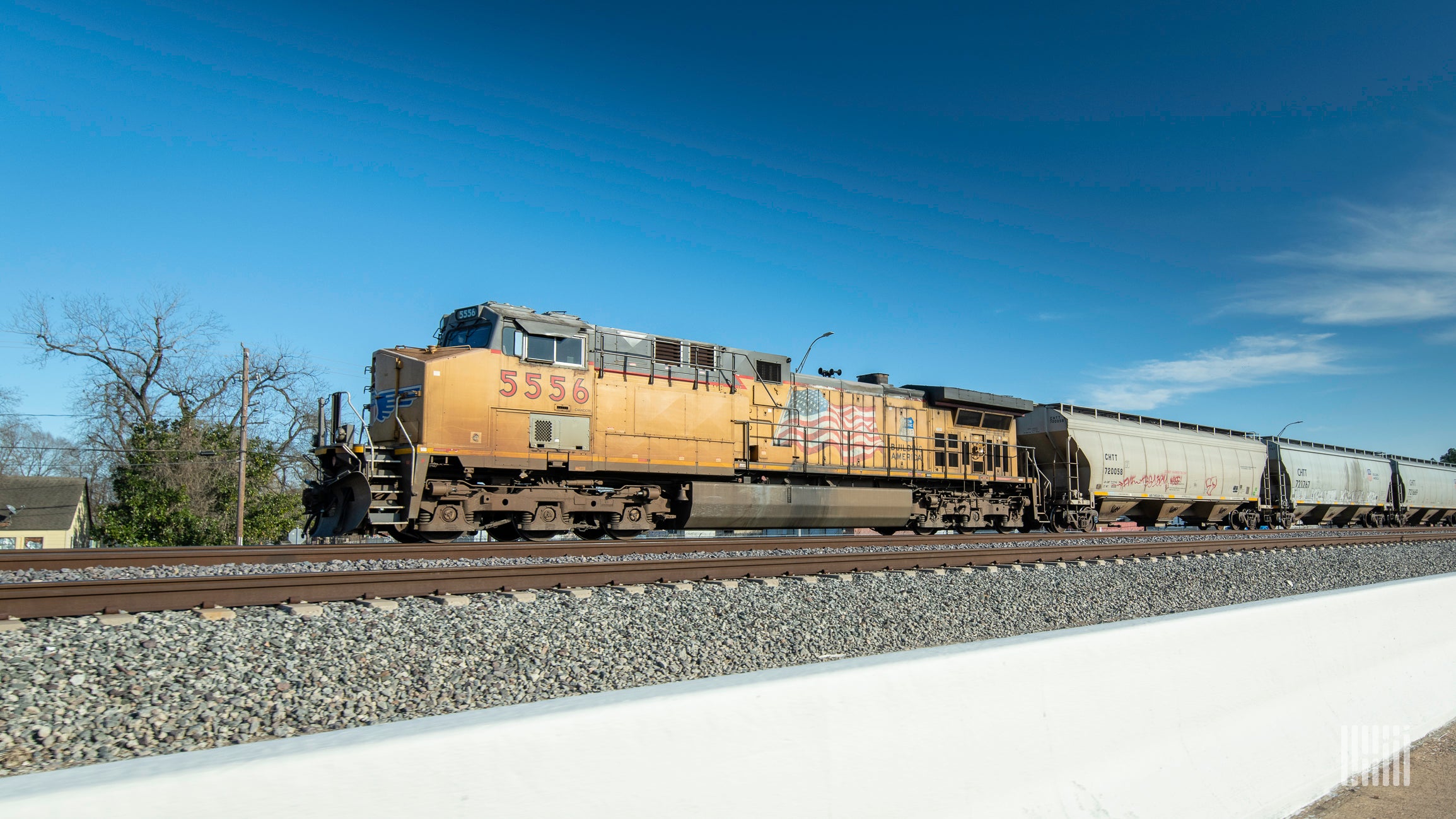 A locomotive hauls railcars down the railroad track.