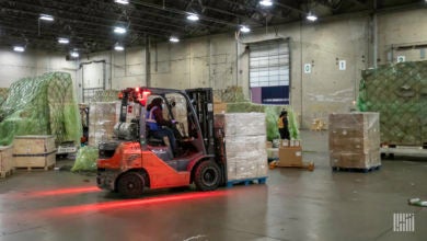 A forklift operator picks up pallets in a warehouse.