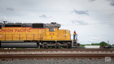 A man stands in front of a parked locomotive.