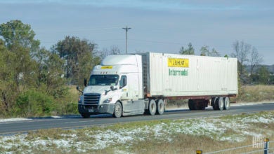 A white J.B. Hunt tractor pulling a white 53-foot intermodal container on a chassis