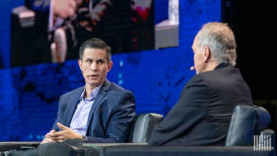 Two white guys discussing issues on stage at a conference.