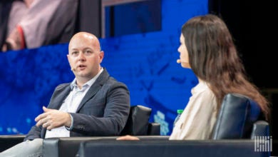 A man and a woman have a discussion on stage at a conference.