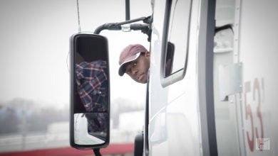 Truck driver leaning out window.