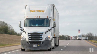 A white Werner tractor pulling a white trailer on the highway