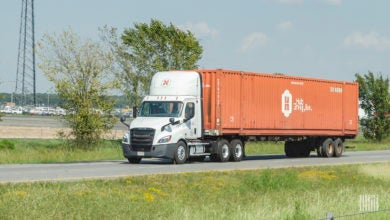 A white Hub Group truck pulling an orange 53-foot container