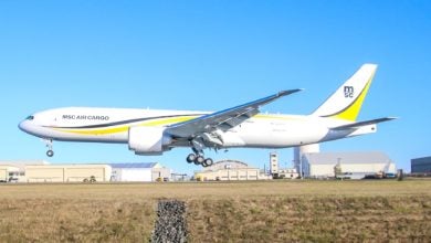 A white 777 cargo jet with MSC Air Cargo lettering and yellow accents ready to touch down on runway.