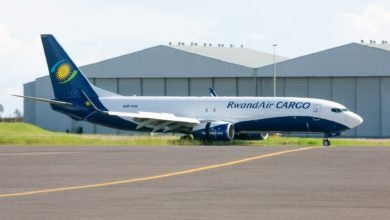 A white-and-blue RwandAir cargo jet at an airport.