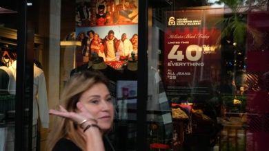 Woman walks past a sales sign in a store window