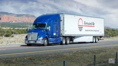 A blue tractor pulling a white Forward Air trailer